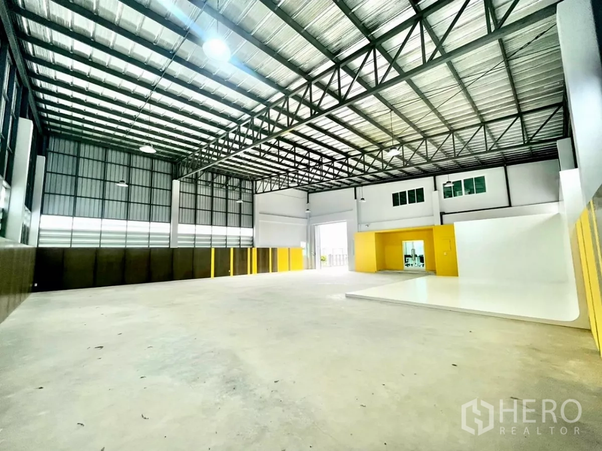 Warehouse for sale in Lam Luk Ka, Pathum Thani - Open warehouse hall with high-clearance steel trusses and yellow accent walls.