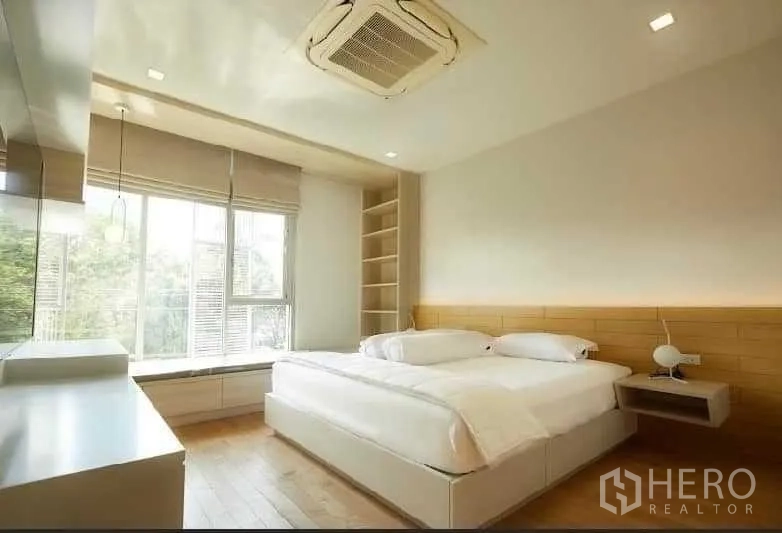 联排别墅 出租在Huai Khwang, Bangkok - 主卧明亮，落地窗、木地板与内置置物架，配色素雅。
