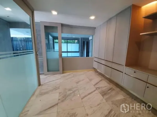 Office Space for rent in Khlong Toei, Bangkok - Compact office room with glass partition, built-in storage and marble tile flooring.