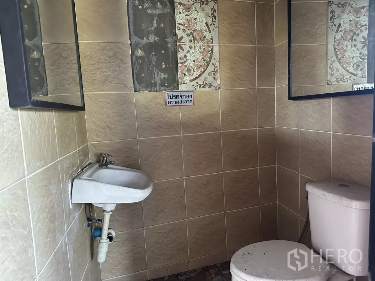 Shophouse for rent in Bang Na, Bangkok - Tiled restroom with toilet, wall mirrors and a compact hand basin.