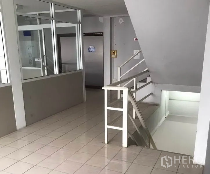 Factory for rent in Bang Bua Thong, Nonthaburi - Stairwell and small lobby beside glass office partitions on tiled flooring.