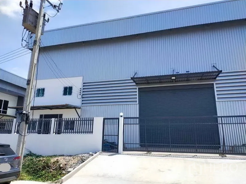 Factory for rent in Samut Prakan - Front loading bay featuring a large roller door and metal canopy at the factory.