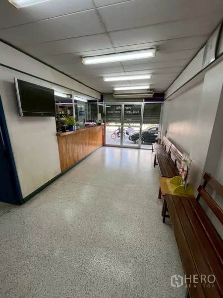 Shophouse for rent in Bang Na, Bangkok - Ground-floor retail space with glass storefront, reception counter, fluorescent lighting and benches.