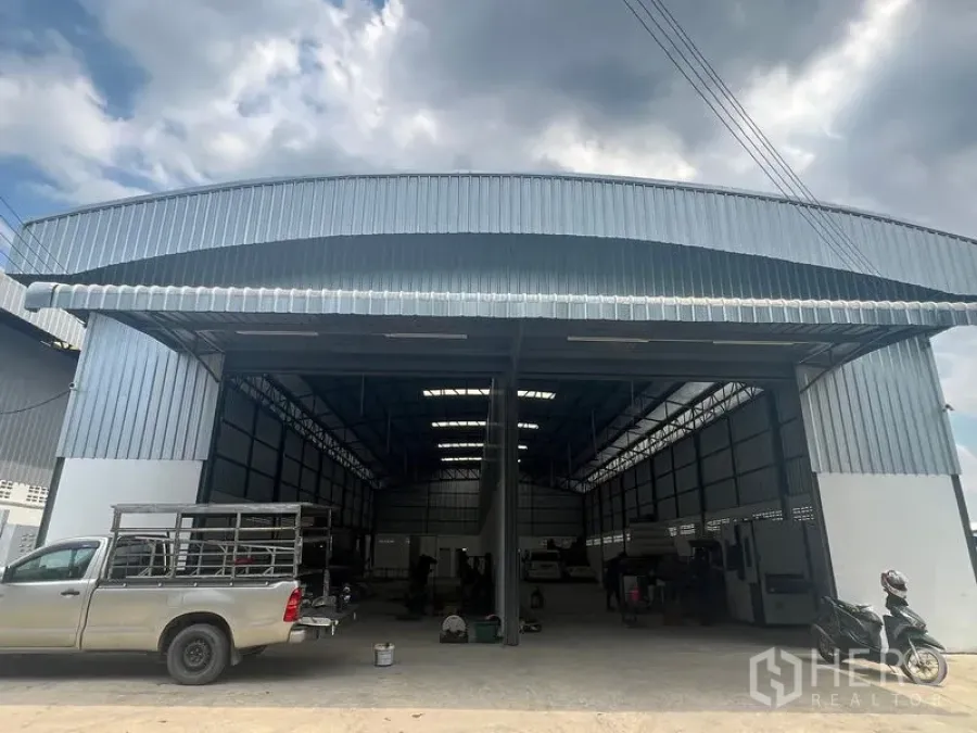 Warehouse for rent in Khlong Sam Wa, Bangkok - Wide facade of the industrial warehouse with metal roof canopy and easy drive-in access for pickups and trucks.