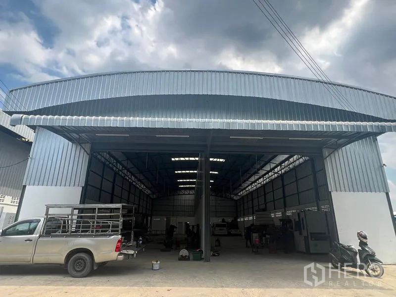 Warehouse for rent in Khlong Sam Wa, Bangkok - Wide facade of the industrial warehouse with metal roof canopy and easy drive-in access for pickups and trucks.