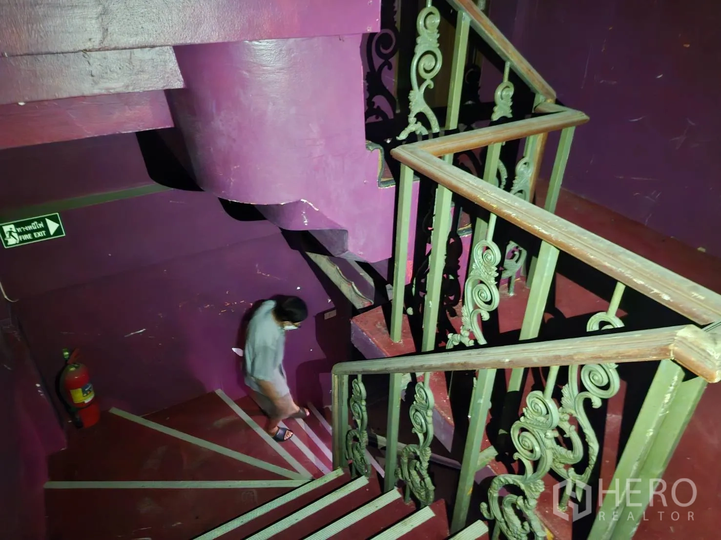 Shophouse for rent in Bang Rak, Bangkok - Stairwell with ornate railings, purple walls and a fire-exit sign.