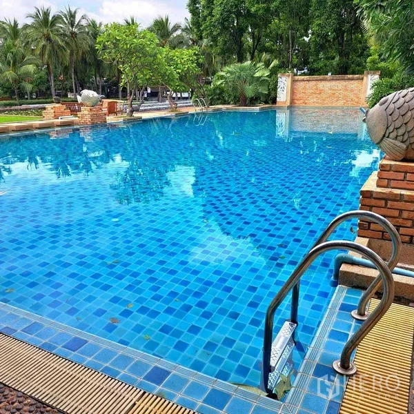 Detached House for rent in Prawet, Bangkok - Large communal swimming pool with blue mosaic tiles, metal ladder and lush trees around.