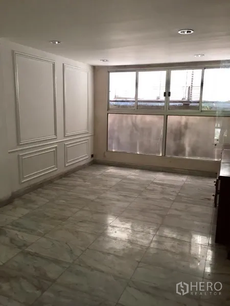 Townhouse for rent in Watthana, Bangkok - Spacious room with marble tiles, wall molding and large frosted windows.