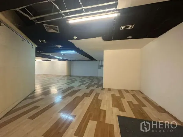 Retail Space for rent - Long, column-free sales floor featuring timber-look flooring and exposed ceiling fixtures.