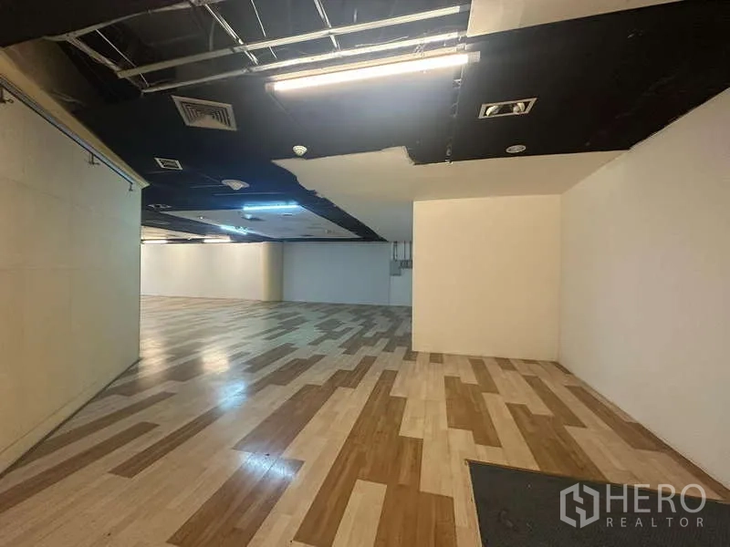 Retail Space for rent - Long, column-free sales floor featuring timber-look flooring and exposed ceiling fixtures.