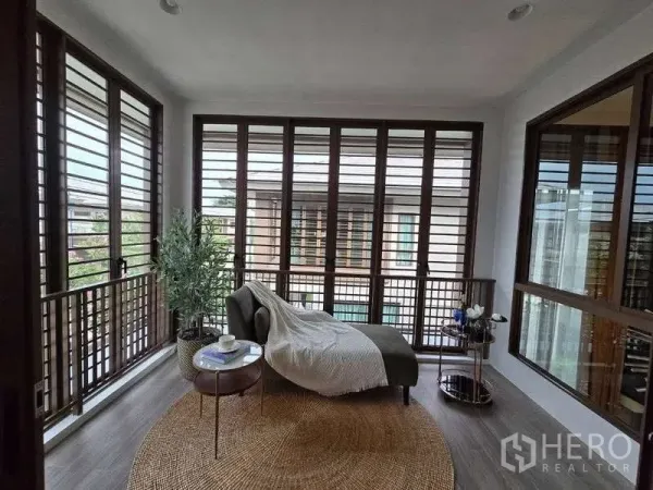Detached House for rent in Bang Kapi, Bangkok - Enclosed sunroom balcony with full-height louvered windows and a lounge chair.