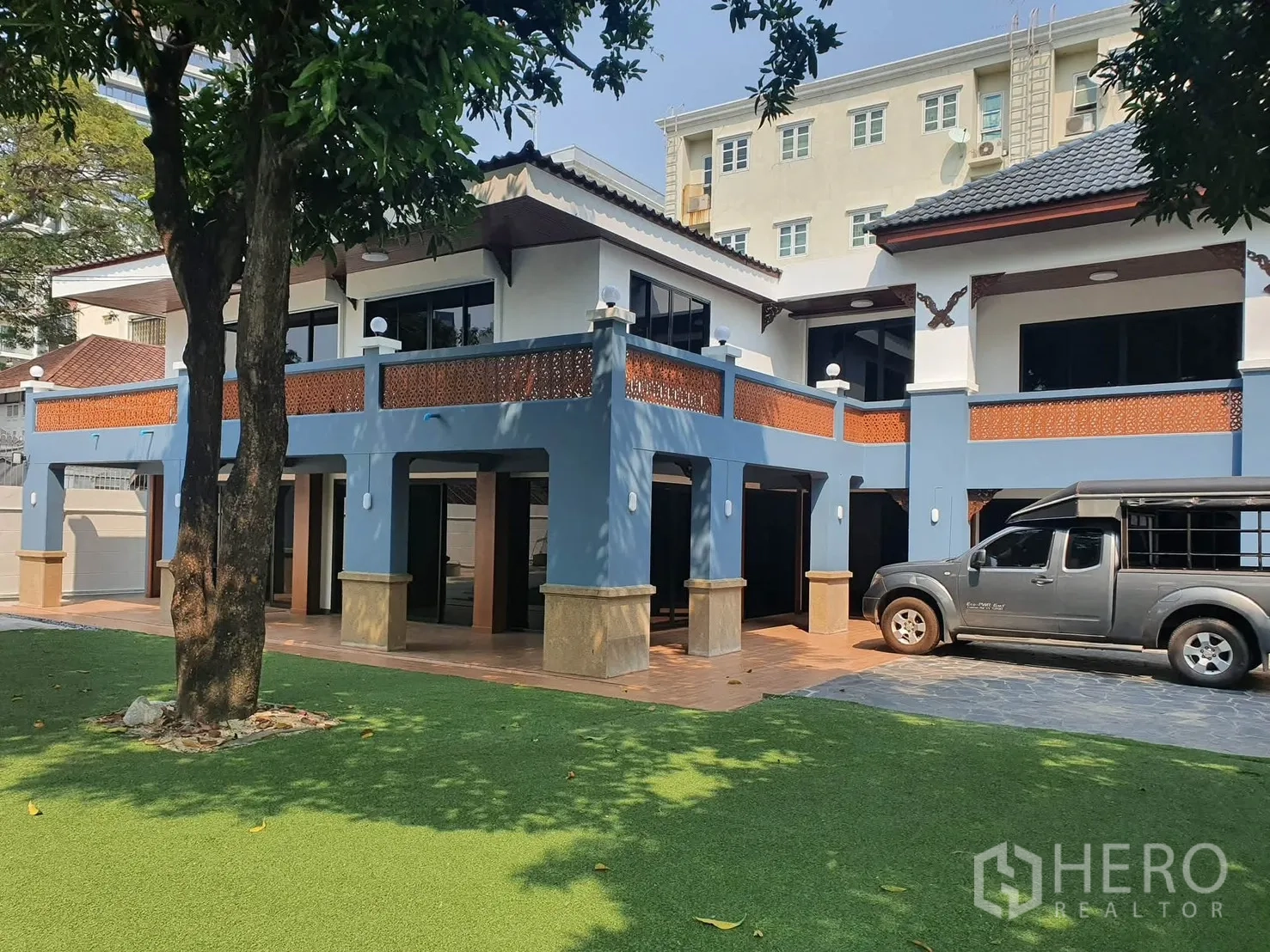 独栋房屋 for rent in Sathon, Bangkok - 蓝白两层住宅外观，设有有顶停车位与宽阔走廊。