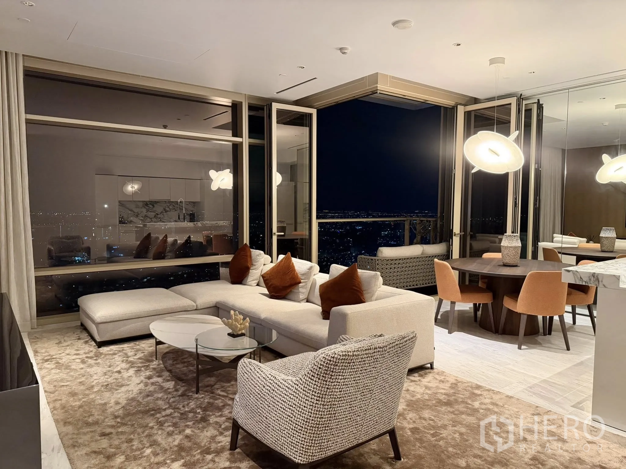 Condominium for rent in Sathon, Bangkok - Open-plan living and dining room with floor-to-ceiling windows, balcony doors, modern pendant lighting, and a sweeping night city view.