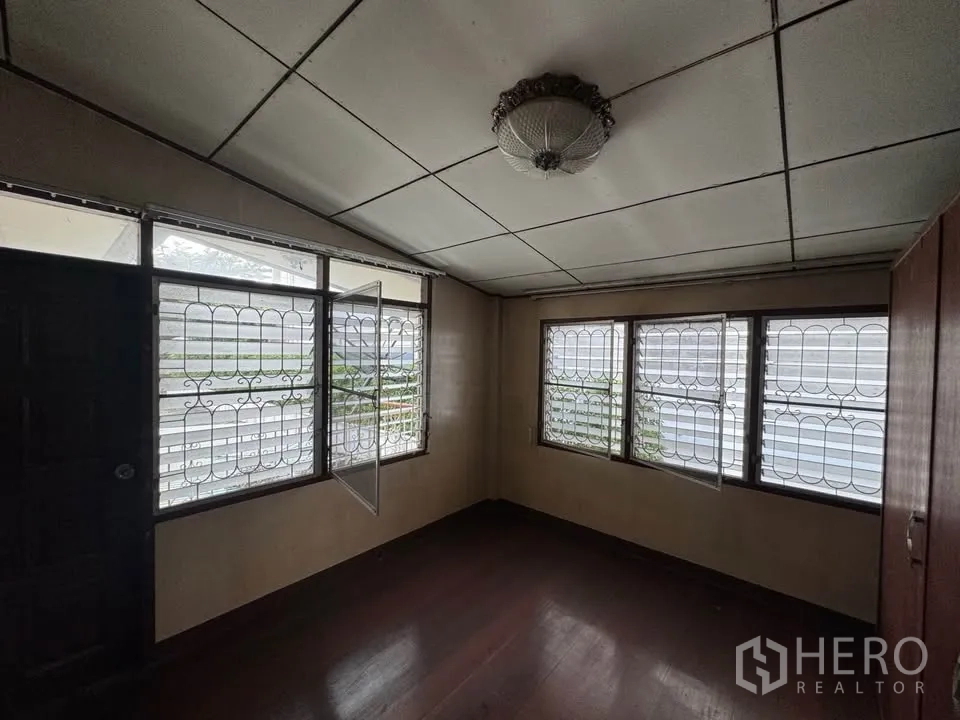 Detached House for rent or sale in Watthana, Bangkok - Compact bedroom with multiple windows and vintage ceiling light.