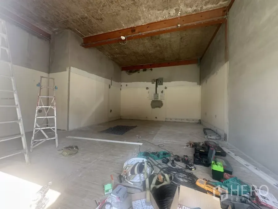 Retail Space for rent in Bang Na, Bangkok - Unfurnished retail unit under renovation with high ceiling, exposed beams, ladders and tools across an open-plan floor.