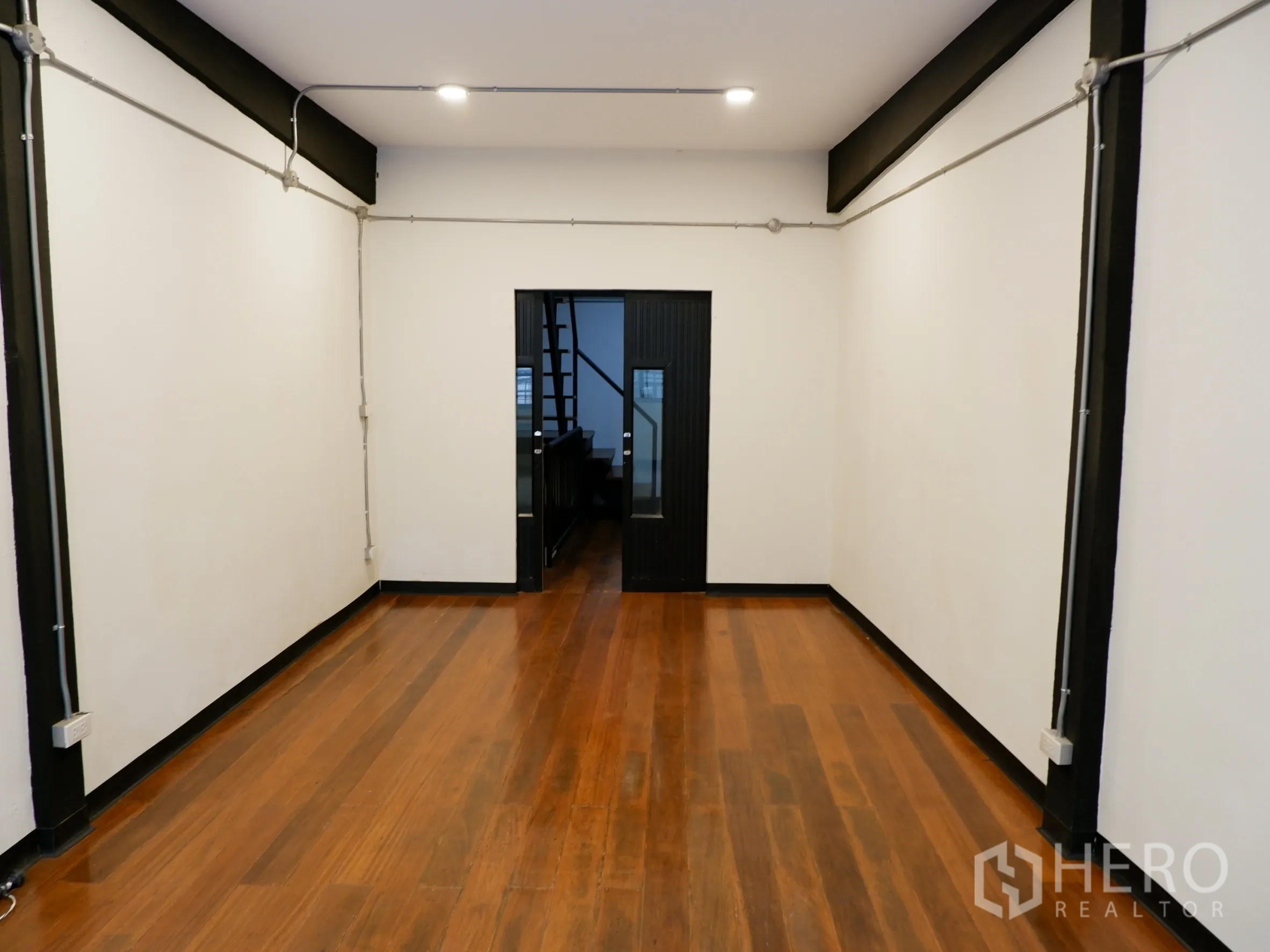 Home Office for sale in Bang Rak, Bangkok - Upper-level workspace with polished wood flooring and exposed conduit lighting.