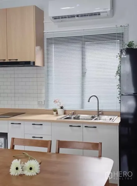 Townhouse for rent in Bang Phli, Samut Prakan - Bright built-in kitchen with wood countertop, double sink, subway tiles and window blinds.