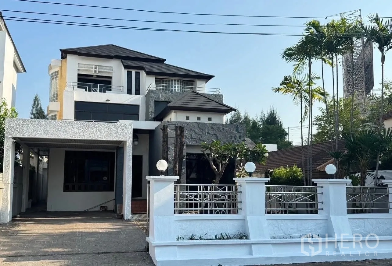 Detached House for rent in Suan Luang, Bangkok - Modern three-storey detached house with white fence, landscaped trees and a covered carport.