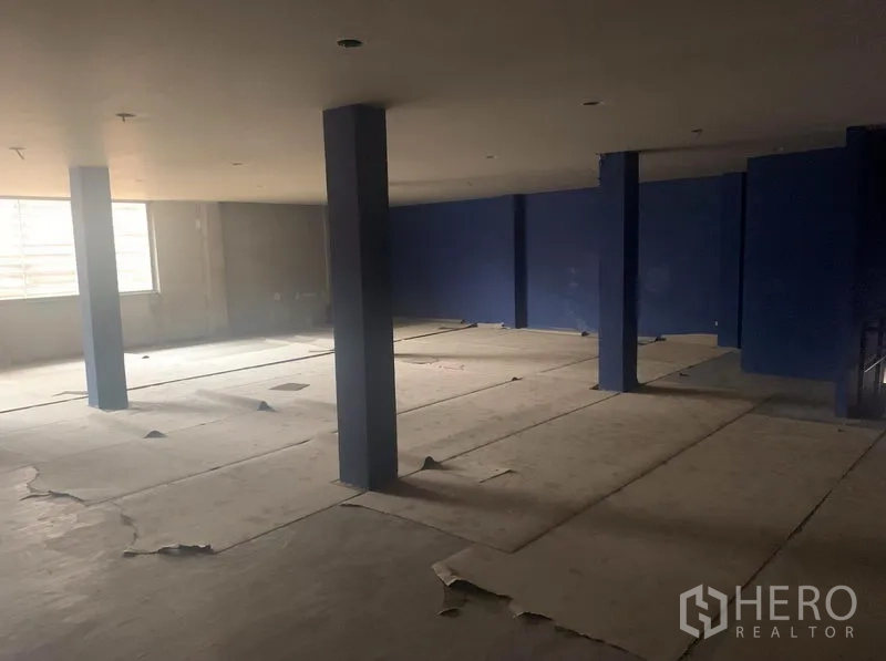 Shophouse for rent in Watthana, Bangkok - Large open-plan upper level with window light, blue feature walls, and columns.