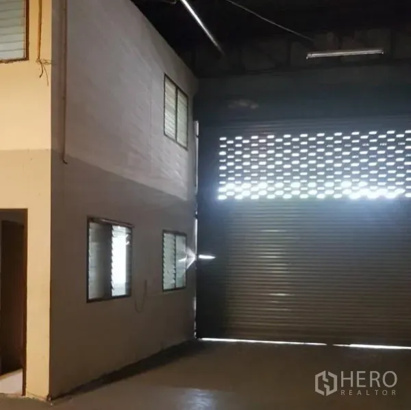 Warehouse for rent in Khlong Luang, Pathum Thani - Warehouse interior with large roller shutter door, mezzanine office and louvered windows.