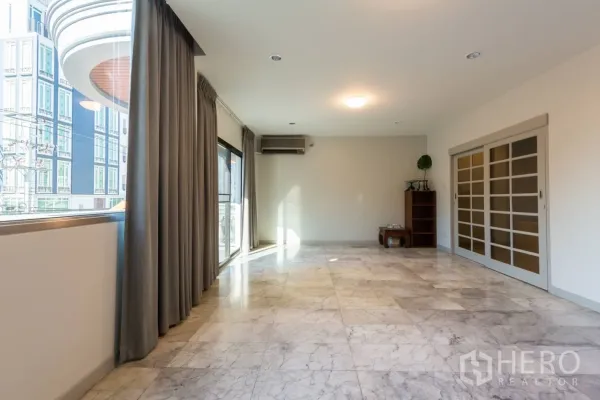 Home Office for rent in Bang Rak, Bangkok - Bright living area with large windows, marble floors and sliding doors to a balcony.