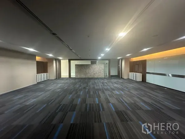 Office Space for rent in Khlong Toei, Bangkok - Large carpeted workspace with glass partitions and ceiling lights.