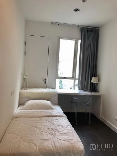 Condominium for rent in Pathum Wan, Bangkok - Cozy single bedroom with a study desk by the window and grey curtains.