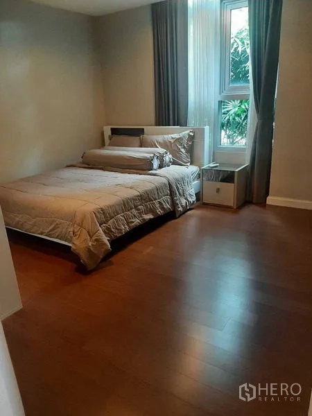 Condominium for rent or sale in Huai Khwang, Bangkok - Cozy bedroom with a double bed and corner window with green views.