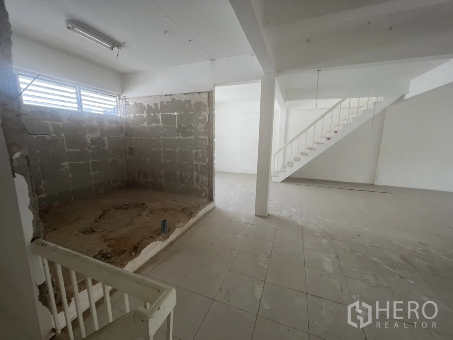 Shophouse for rent in Watthana, Bangkok - Open level with tiled flooring, partial brick wall and stair access.