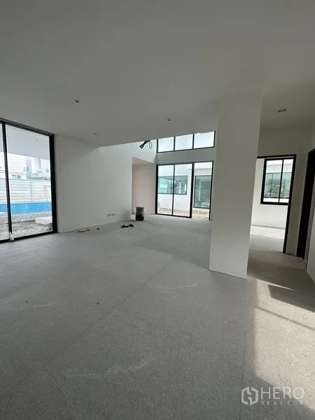 Detached House for rent in Watthana, Bangkok - Spacious living area with large windows and sliding doors facing the yard and pool area.