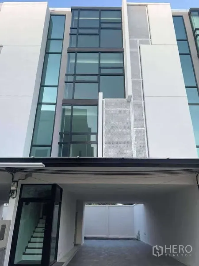 Home Office for rent in Bang Khen, Bangkok - Ground-level entry with a glass door and shaded parking area beneath the building.