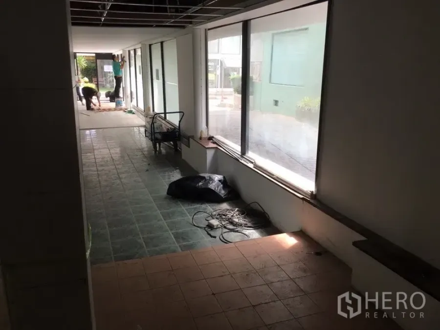 Retail Space for rent in Watthana, Bangkok - Long retail interior with floor-to-ceiling windows, tiled floors, exposed ceiling grid and renovation materials allowing abundant natural light.