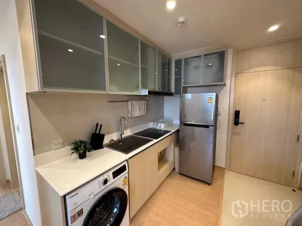 Condominium for sale - Modern galley kitchen with built-in cabinets, hob, sink, fridge and washing machine.