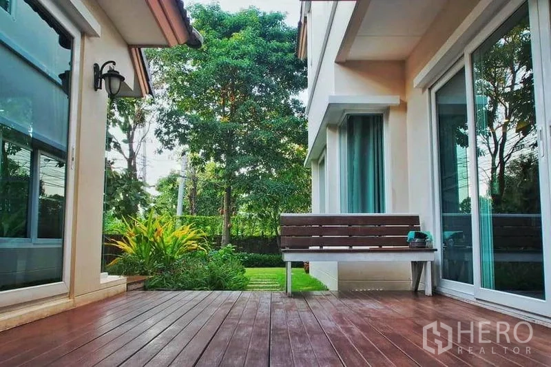 Detached House for rent or sale in Pak Kret, Nonthaburi - Wooden deck terrace with bench seating, sliding glass doors and view to a landscaped garden.