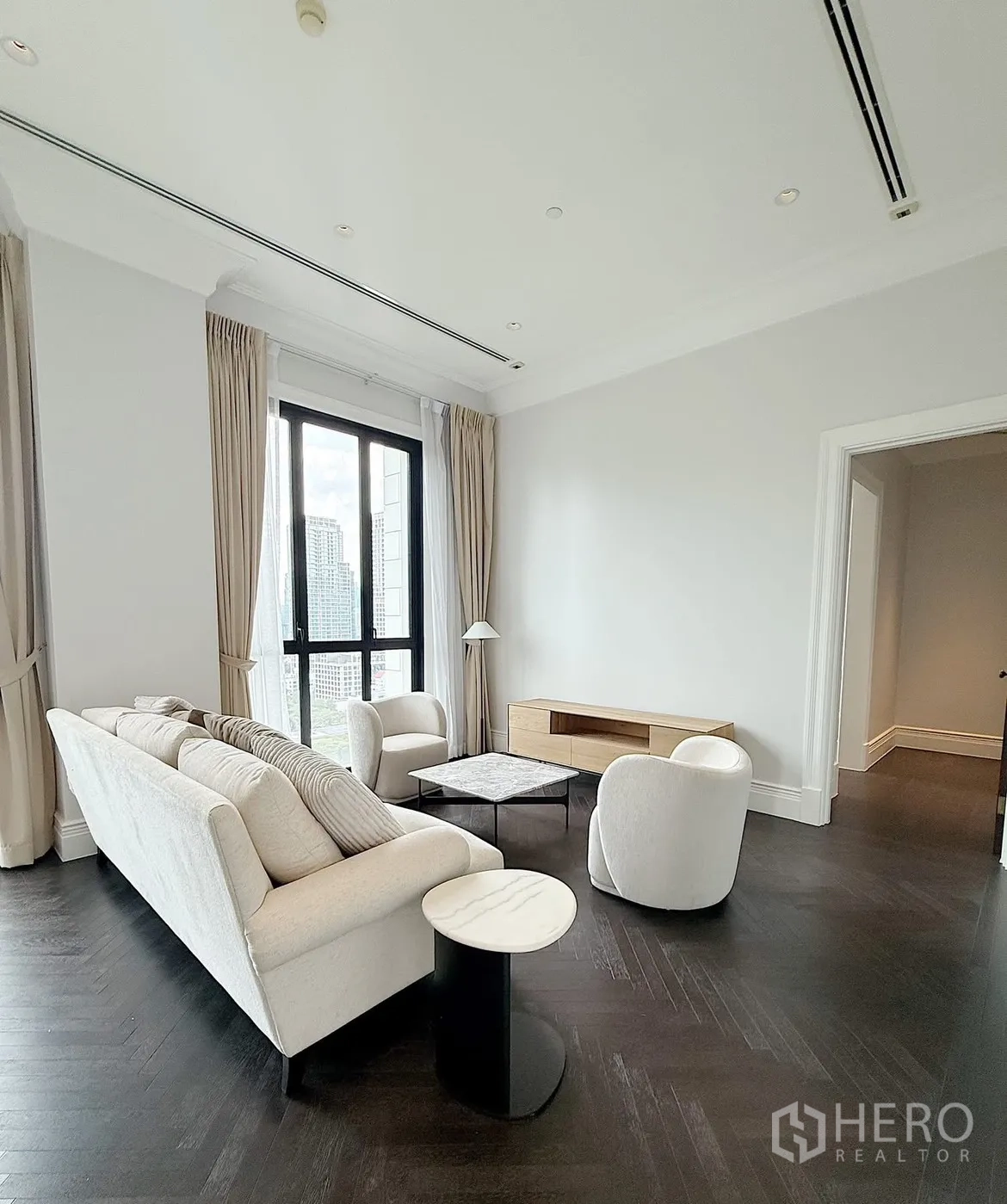 Condominium for rent or sale in Pathum Wan, Bangkok - Minimalist living room featuring a sofa, armchairs, marble coffee table, and media console.
