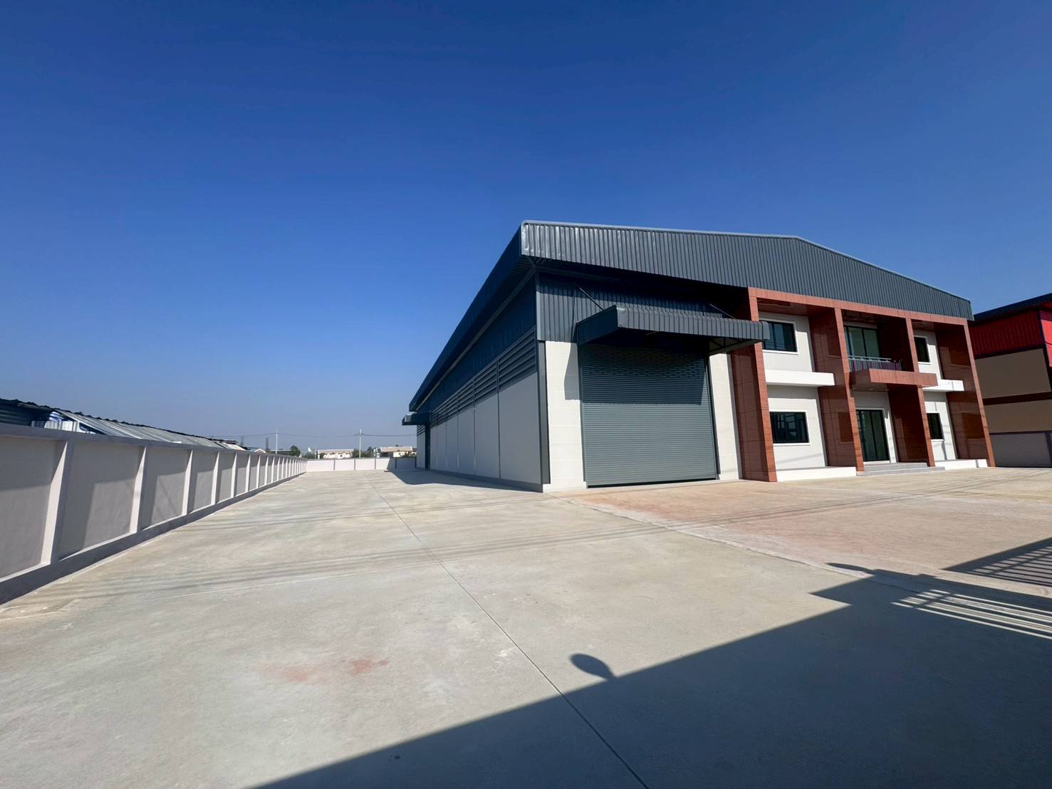 Factory for sale in Mueang Samut Sakhon, Samut Sakhon - Wide concrete yard beside the factory building, suitable for truck turning and parking.