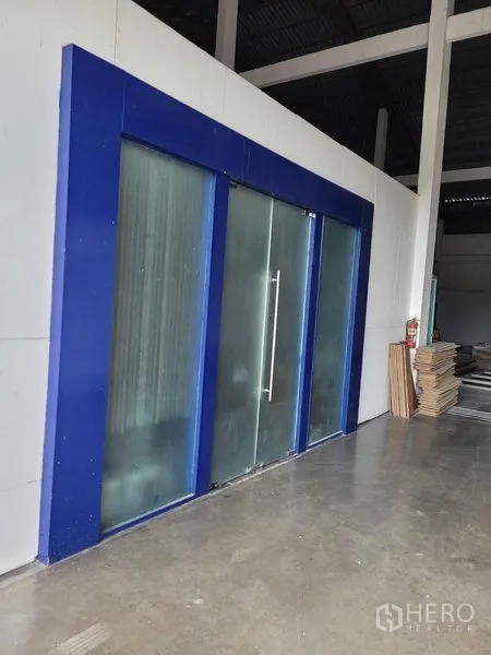 Warehouse for rent in Phra Khanong, Bangkok - Sliding glass entry with a blue frame leading to the internal office section of the warehouse.