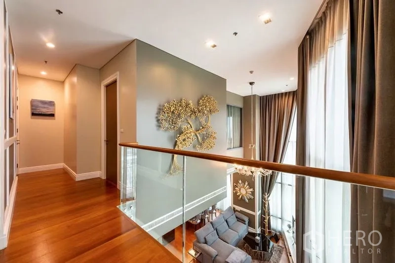 Condominium for rent in Khlong Toei, Bangkok - Upper mezzanine landing with glass railing overlooking the living room.
