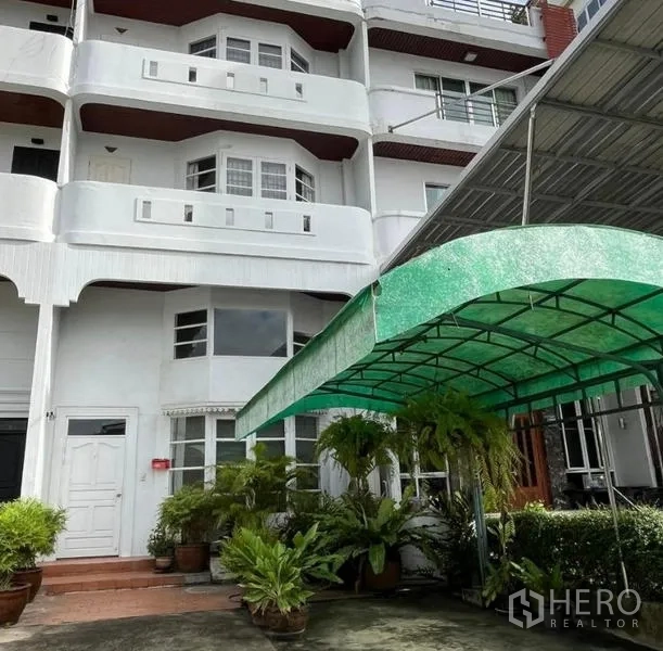 Home Office for rent in Bang Rak, Bangkok - Multi-storey white home office facade with balconies and a green covered carport at the front.