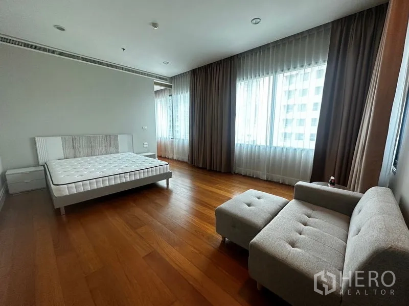 Condominium for rent in Khlong Toei, Bangkok - Large master bedroom featuring sofa seating, multiple windows and curtains.