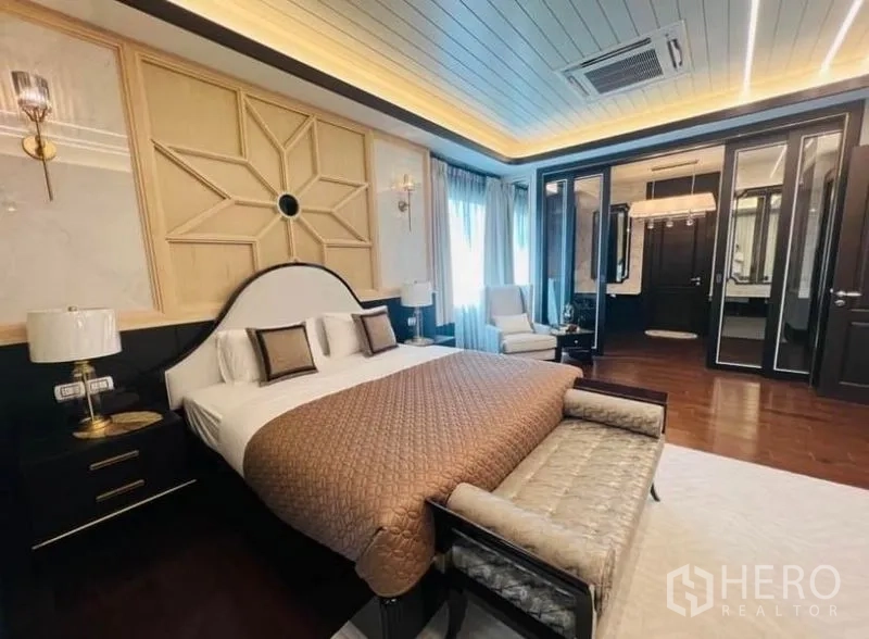 Detached House for rent or sale in Watthana, Bangkok - Primary bedroom with paneled feature wall, bench seat and walk-in ensuite.