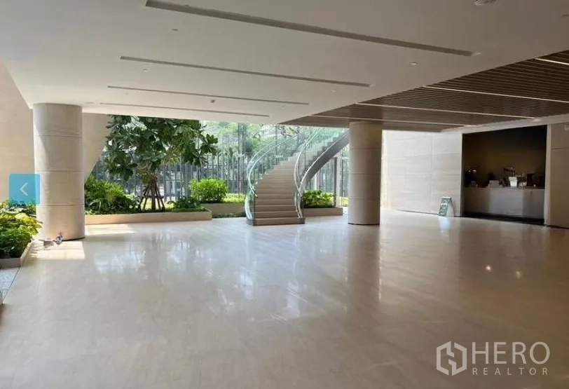 Retail Space for rent - Spacious modern lobby with polished stone floors, indoor planters, floor-to-ceiling glass and a curved glass staircase.