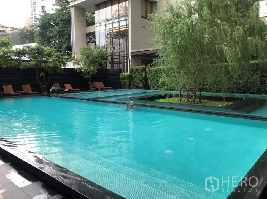 Condominium for rent or sale in Khlong Toei, Bangkok - Resort-style outdoor swimming pool with sun loungers and landscaped garden at a Bangkok condo.