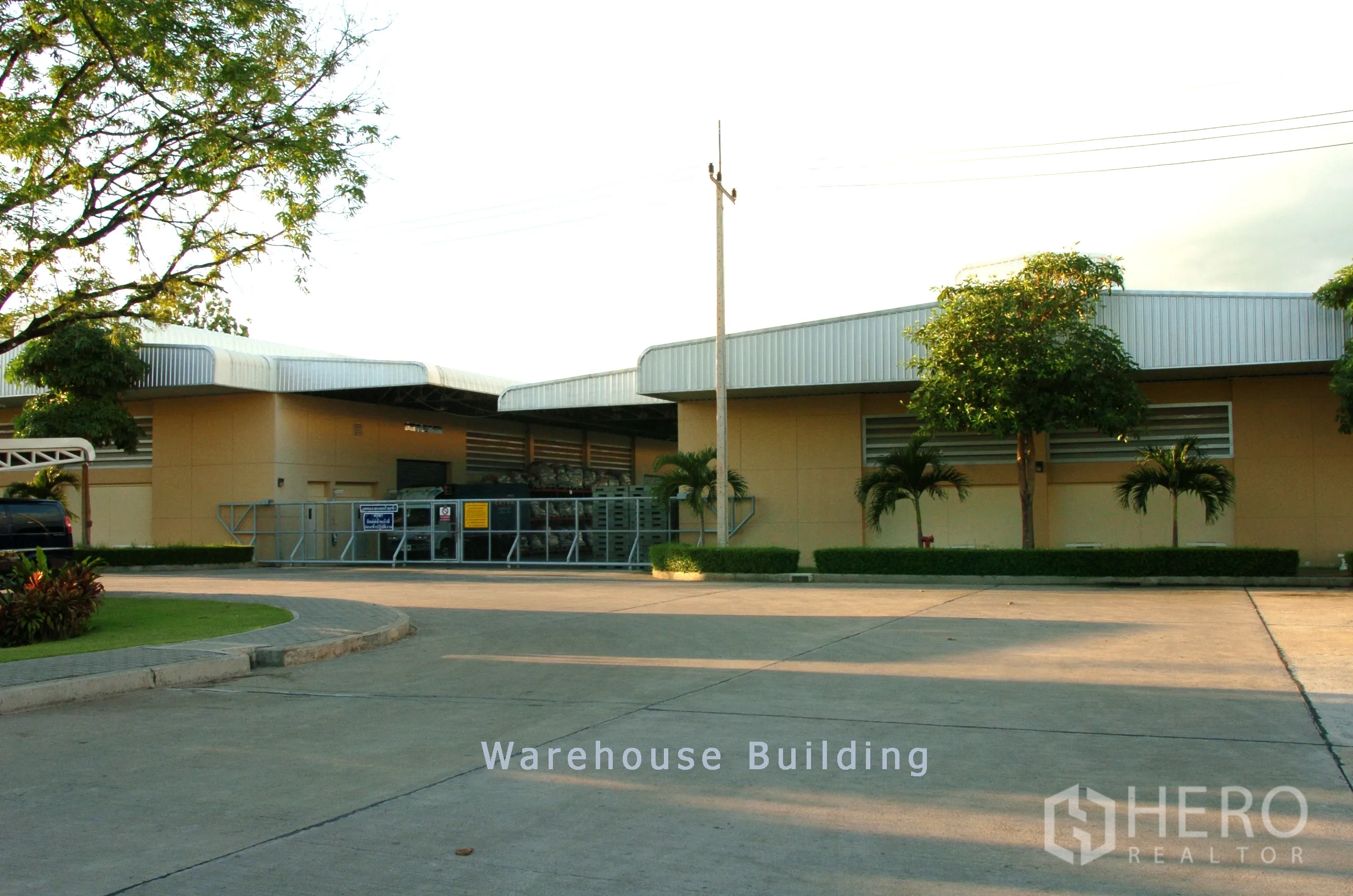 Factory for sale in Khao Chamao, Rayong - Low‑rise warehouse buildings with metal roofs, loading area and a wide driveway for trucks.