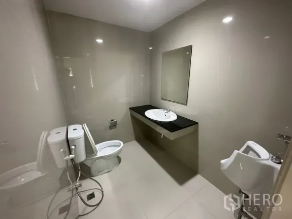 Office Space for rent - Clean office restroom with toilet, urinal, countertop sink and wall mirror.
