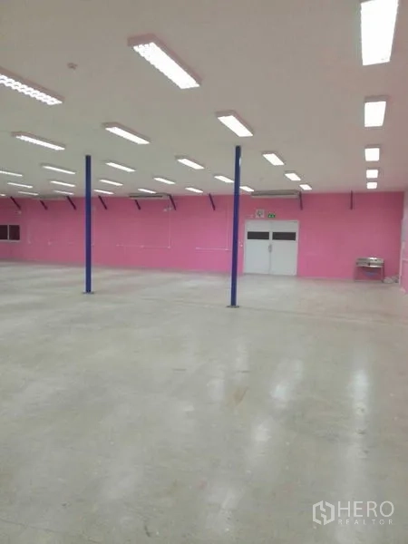 Warehouse for rent in Khlong Luang, Pathum Thani - Wide warehouse hall with bright ceiling lights, support columns and double doors.