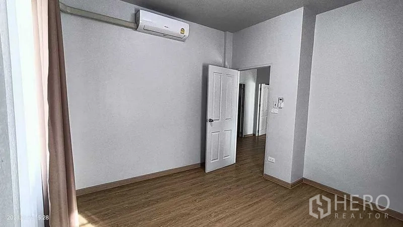 Detached House for rent in Lam Luk Ka, Pathum Thani - Empty bedroom with wood-look floor and wall-mounted air conditioner.