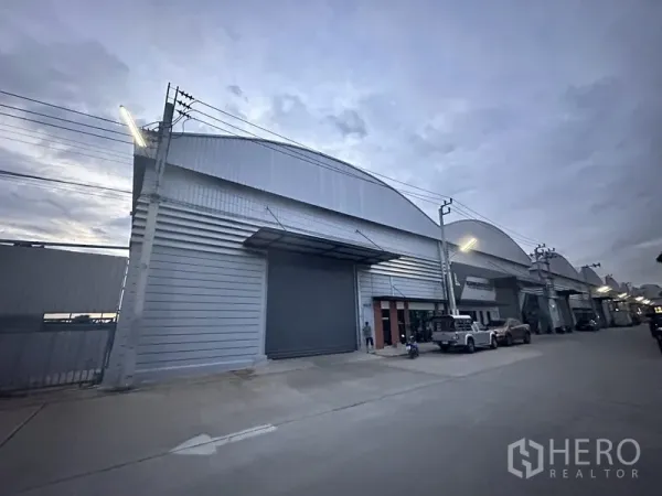 คลังสินค้า ให้เช่าในBang Phli, Samut Prakan - ด้านหน้าโกดังยามค่ำพร้อมไฟถนนและประตูม้วนปิด