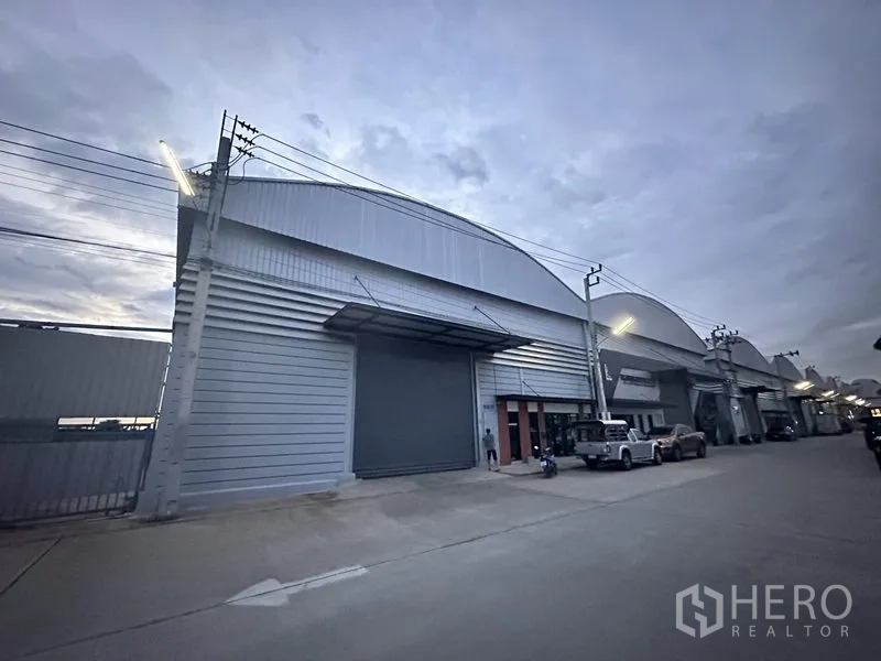 คลังสินค้า ให้เช่าในBang Phli, Samut Prakan - ด้านหน้าโกดังยามค่ำพร้อมไฟถนนและประตูม้วนปิด