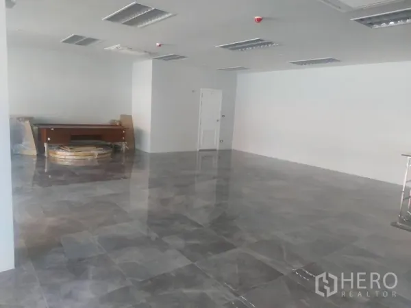 零售空间 出租 - 宽敞空铺，抛光地砖、白色墙面与天花灯，后方有房门。